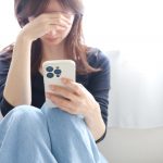 スマホを持って悩んでいる女性