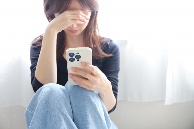 スマホを持って悩んでいる女性